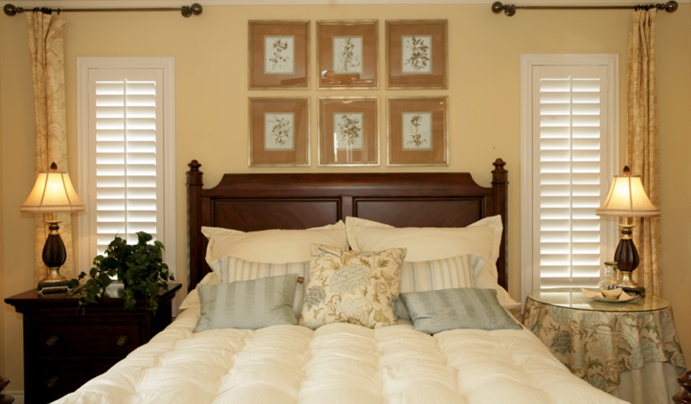 Bedroom with two tall plantation shutters on either side of bed in San Diego 